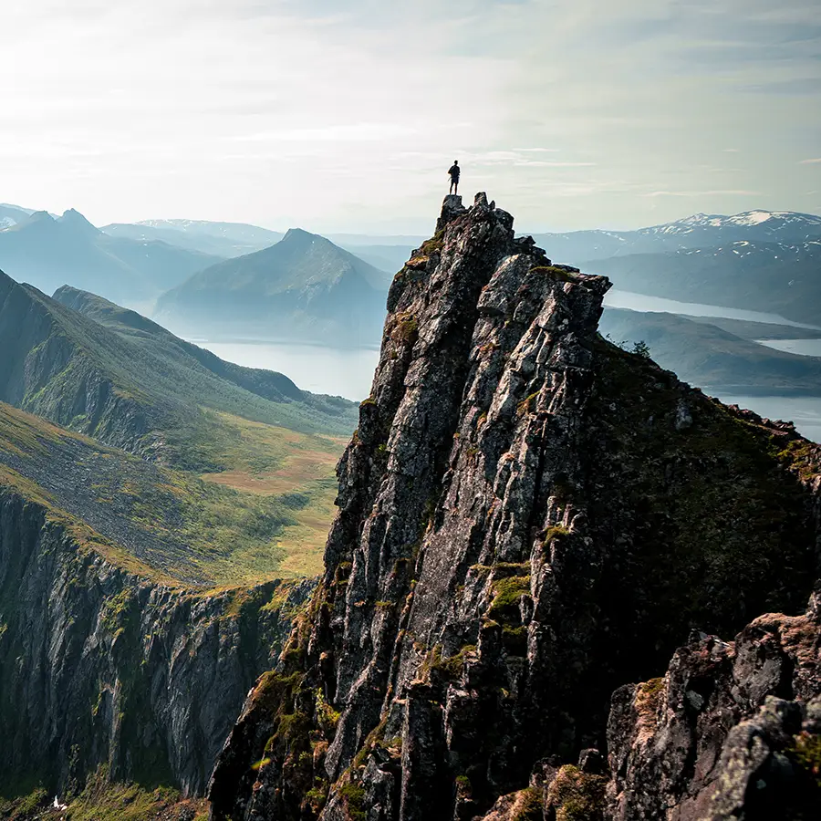 Person steht oben auf einem Berggipfel